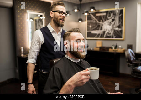 Portrait of happy barber and customer drinking coffee in salon Stock Photo