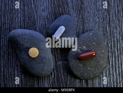 Medicine pills or drug pills on pebble stones. These could be medical or pharmaceutical or street drugs. Stock Photo