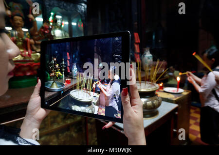 Woman using Ipad tablet to take a photograph.  Taoist temple. Emperor Jade pagoda (Chua Phuoc Hai).  Woman using Ipad tablet to take  photographs of c Stock Photo