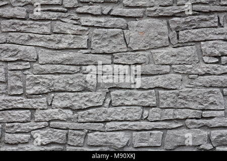 Dark grey stone wall texture made from various large and small stones Stock Photo