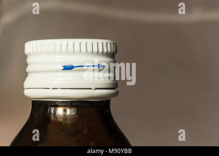 Macro photo of a dark bottle with medicine and a white lid. Blue arrow on the side of the lid. Site about medicine, health. Stock Photo