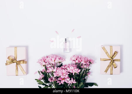Bouquet of pink flowers, toilet water, and gift boxes with ribbons on a white table top view Stock Photo