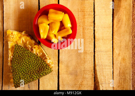 Top view of red bowl with jackfruit pods and jackfruit skin isolated on wooden background Stock Photo