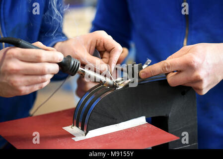 Two blue collar workers soldering electrical transformer in close up Stock Photo