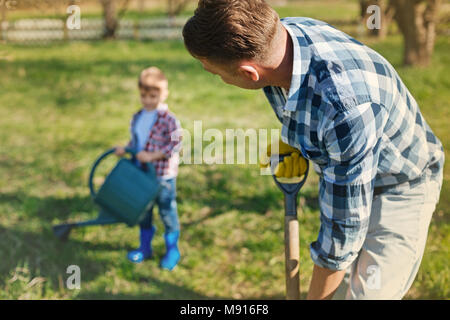 Pleasant adult man digging the ground in the garden Stock Photo