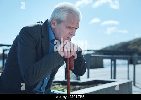Upset old man thinking about something outdoors Stock Photo