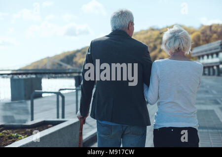 Senior couple walking along riverwalk Stock Photo