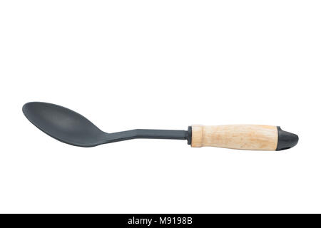 Big black plastic stirring spoon with wooden handle isolated on white background. Kitchen accessory. Path saved Stock Photo
