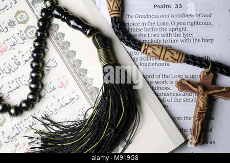 Christianity, Islam 2 monotheistic religions. Bible and Quran. Crucifix and prayer beads. Interfaith symbols. Stock Photo