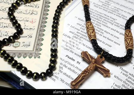 Christianity, Islam 2 monotheistic religions. Bible and Quran. Crucifix and prayer beads. Interfaith symbols. Stock Photo