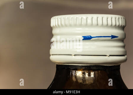 Macro photo of a dark bottle with medicine and a white lid. Blue arrow on the side of the lid. Site about medicine, health. Stock Photo