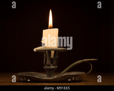 Nearly burnt down burning candle on an old metallic candle holder Stock Photo