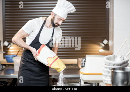 Baker filling flour into the kneader Stock Photo