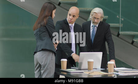 multiethnic corporate people meeting in office discussing business using laptop computer in modern office. Stock Photo