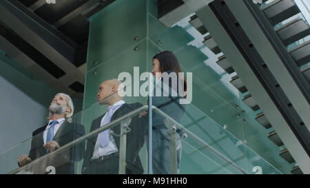 three multinational company executives standing on second floor of modern office building discussing business. Stock Photo