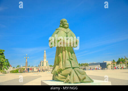 Fatima, Portugal - August 15, 2017: behind Pope Statue looking Sanctuary of Nossa Senhora of Fatima on blurred background. Fatima is one of the most famous travel destinations for Catholic pilgrimage. Stock Photo