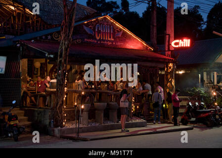 The main street in Ella evening night time showing a typical restaurant, bar filled with tourists.  Slow shutter speed and high iso so motion blur. Stock Photo