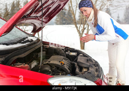 Confused young woman looking at broken down car engine car 