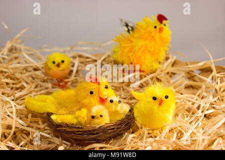 Easter decorations. In the wicker basket are straw chickens and hen. In the brood are too chickens and hen. Stock Photo