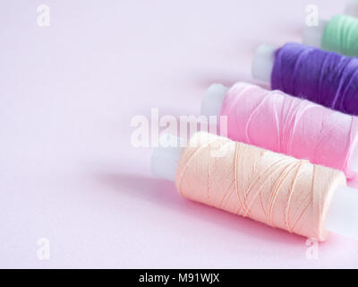 Colorful sewing buttons and thread on a pink background Stock Photo