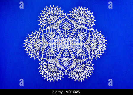 Crocheted lace napkin as home decoration on blue Stock Photo