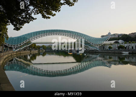 The Peace Bridge across the Mtkvari River and Presidential Palace on a hill in the background, Tbilisi, Georgia Stock Photo