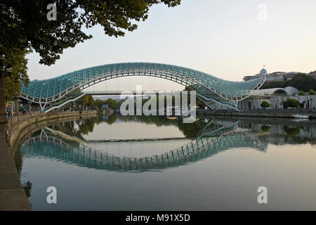 The Peace Bridge across the Mtkvari River and Presidential Palace on a hill in the background, Tbilisi, Georgia Stock Photo