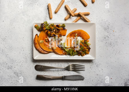 sliced baked pumpkin, with broccoli and assorted vegetables, on rectangular white plate, from above Stock Photo