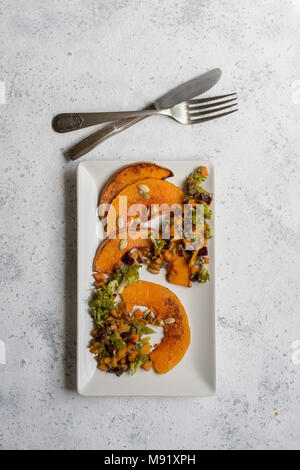 sliced baked pumpkin, with broccoli and assorted vegetables, on rectangular white plate, from above Stock Photo