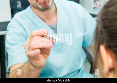 Close up doctor testing reflexes of the eye of young woman using a lamp in medical clinic. Neurological physical examination. Selective focus, space for text. Stock Photo