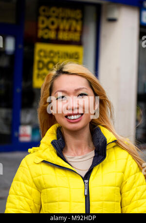 A Scottish born Chinese woman with a happy smiling face posing to have her photograph taken on a windy day in Dundee, UK Stock Photo