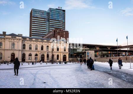 Oslo, Norway - March 16, 2018 - Oslo Central Station, day, people walking, snow on the ground. The Post Office Building in the background. Stock Photo