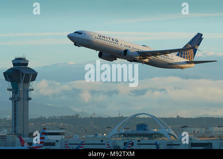 United Airlines Boeing 737-900 Jet Airliner Taking Off From Los Angeles International Airport, LAX. The Theme Building And Control Tower Behind. Stock Photo