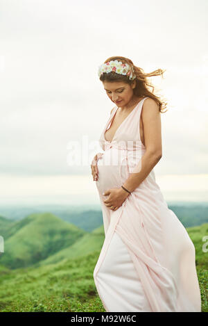 One young pregnant woman in pink dress outside Stock Photo