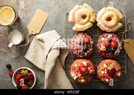 Variety of colorful old fashioned fried gourmet donuts on a cooling rack with glaze Stock Photo