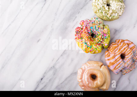 Variety of colorful old fashioned fried gourmet donuts on a marble surface with glaze Stock Photo