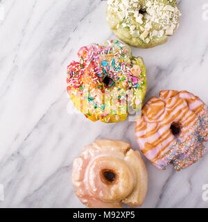 Variety of colorful old fashioned fried gourmet donuts on a marble surface with glaze Stock Photo