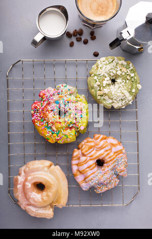 Variety of colorful old fashioned fried gourmet donuts on a cooling rack with glaze Stock Photo