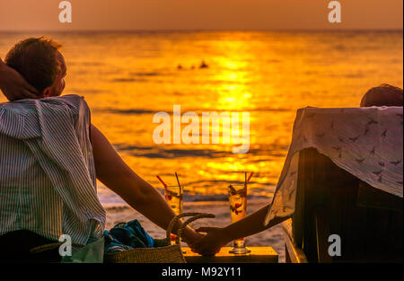 View on couple enjoying sunset with Coctails on Koh Kood beach in Thailand Stock Photo