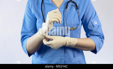 Female doctor putting on rubber gloves, protective uniform, laboratory worker Stock Photo