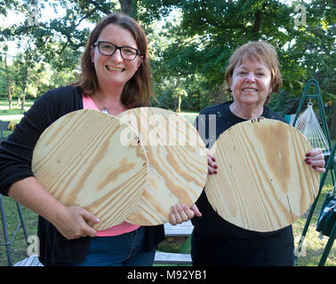 Two proud women holding up circle cut-outs they just made from a sheet of plywood for remodeling barstool seats. Clitherall Minnesota MN USA Stock Photo