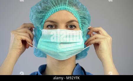 Surgeon putting on mask, doctor preparing for the procedure, examining patient Stock Photo