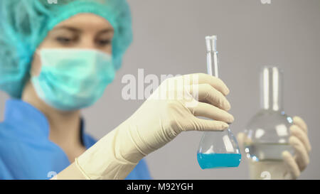 Female chemist holding tubes with liquid, working in laboratory on vaccine Stock Photo