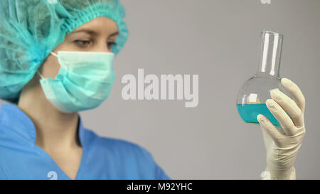 Female scientist analyzing chemical reaction in laboratory tube, experiment Stock Photo