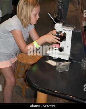 Girl age 10 adjusting lens of microscope at the Science Museum of Minnesota exhibit St Paul Minnesota MN USA Stock Photo