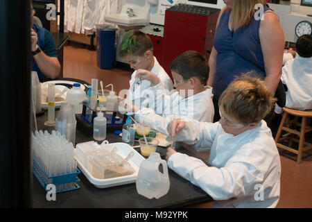 Young scientists age 10 working in the Science Museum of Minnesota laboratory with mom watching. St Paul Minnesota MN USA