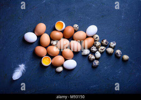 Eggs on a wooden table styled with feathers and eggshells. Cooking ingredients. Top view. Stock Photo