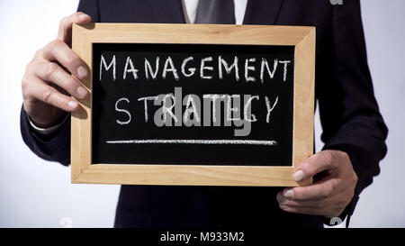 Management strategy written on blackboard, businessman holding sign, concept Stock Photo