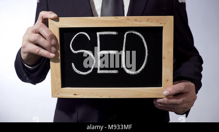SEO written on blackboard, businessman holding sign, business concept, strategy Stock Photo