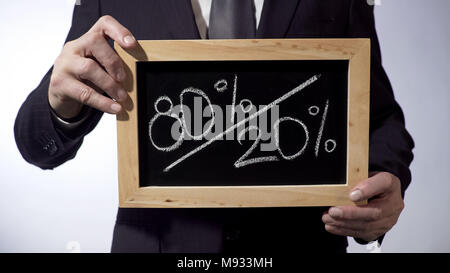 80 to 20 percent written on blackboard, man holding sign, Pareto principle Stock Photo